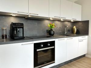 a kitchen with white cabinets and a black appliance at Neu & Schick: Küche inkl. Kaffee in Dresden
