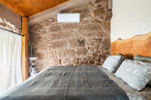 a bed in a room with a stone wall at Segredos da Montanha - Mangualde in Mangualde