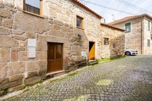 a stone building with a door on a street at Segredos da Montanha - Mangualde in Mangualde