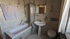 a bathroom with a sink and a tub and a toilet at Ferienwohnung am Frauenbach in Chieming