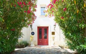 una puerta roja en una casa blanca con flores en Hôtel de Margaux, en Margaux