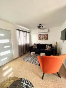 a living room with a black couch and orange chair at stylish studio w/backyard space near airport in Carolina