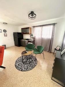 a living room with two green chairs and a table at stylish studio w/backyard space near airport in Carolina