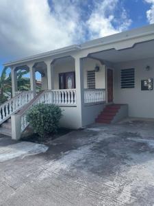 a white house with a staircase in front of it at Mountain view Apartment in Basseterre