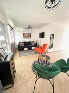 a living room with a black couch and orange chairs at stylish studio w/backyard space near airport in Carolina