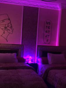 a bedroom with two beds with purple lights at Sneferu Pyramids inn - Full Pyramids View in Cairo