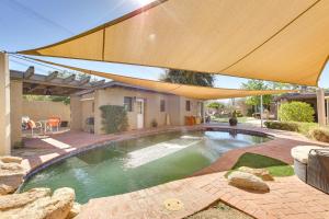 a swimming pool in a backyard with an umbrella at Uptown Phoenix Studio Casita with Outdoor Pool! in Phoenix