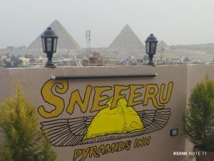 a sign with the pyramids in the background at Sneferu Pyramids inn - Full Pyramids View in Cairo