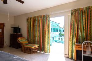 1 dormitorio con puerta corredera de cristal con silla en Ocean View King Room at Sahara Hotel, en Montego Bay