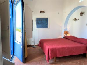 a bedroom with a red bed and a window at Le Case di Eolo in Malfa