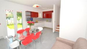 a kitchen and dining room with a table and red chairs at Terraced house with private garden in Bibione