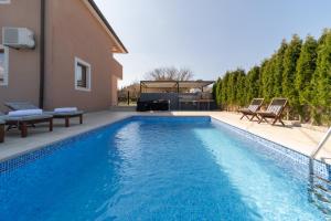 a swimming pool with two chairs and a house at Holiday Home Kiara in Brtonigla