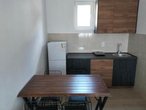 a kitchen with a wooden table and a refrigerator at Talic Apartmani in Sutomore