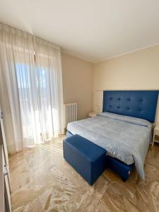 een slaapkamer met een blauw bed en een blauwe poef bij Hotel Riviera in Porto San Giorgio