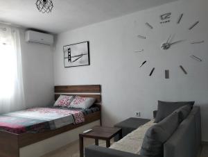 a bedroom with a couch and a clock on the wall at Talic Apartmani in Sutomore