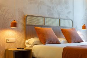 a bedroom with a bed with orange pillows and a table at Jardín Milenio in Elche