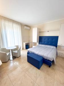 Schlafzimmer mit einem blauen Bett und einem Tisch in der Unterkunft Hotel Riviera in Porto San Giorgio