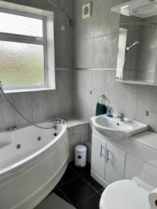 a bathroom with a tub and a sink and a toilet at Rooms at EEJ homes in London