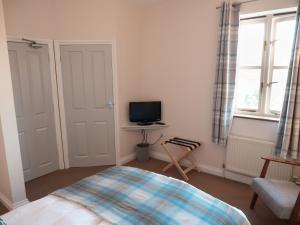 a bedroom with a bed and a tv on the wall at By the River in Glasbury