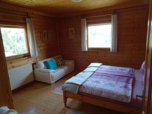 a bedroom with a bed and a couch and two windows at Chalet in Diex near Klopeiner See with sauna in Diex