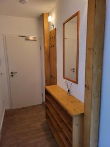 La salle de bains est pourvue d'une commode en bois et d'un miroir. dans l'établissement Ferienwohnung im Dachgeschoss mit Aufzug, à Rostock