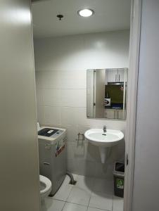 a bathroom with a sink and a toilet and a mirror at Sea Residences MOA -PaulJade Place in Manila