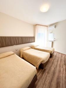 een hotelkamer met 3 bedden en een raam bij Hotel Riviera in Porto San Giorgio