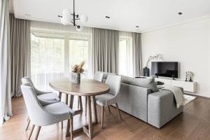 ein Wohnzimmer mit einer Couch und einem Tisch und Stühlen in der Unterkunft Spacious luxury apt w/river view/terrace Paupys in Vilnius