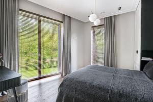 ein Schlafzimmer mit großem Bett und großen Fenstern in der Unterkunft Spacious luxury apt w/river view/terrace Paupys in Vilnius