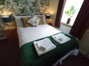 a bedroom with a bed with towels on it at Brackenhurst Guest House in Skegness