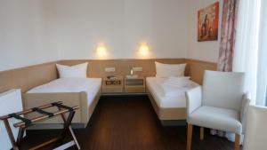 ein Hotelzimmer mit 2 Betten und einem Stuhl in der Unterkunft Hotel Garni Alte Post in Schallbach