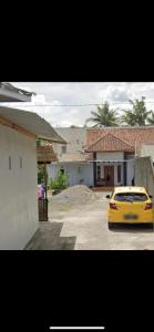 une voiture jaune garée devant une maison dans l'établissement Wisma Sadewa, à Pangenjurutengah