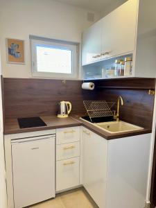 eine kleine Küche mit weißen Schränken und einem Waschbecken in der Unterkunft Apartman Sunce in Vodice