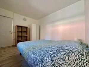 um quarto com uma cama com um edredão azul e branco em 03 T2 Immeuble Le GD em Jarny