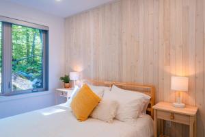 a bedroom with a bed with two lamps and a window at Le coup de coeur du Lac Supérieur - 3 minutes from Tremblant! in Lac-Superieur