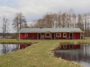 a red house next to a body of water at Holiday home VÅXTORP II in Våxtorp