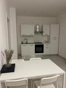 a white kitchen with a white table and chairs at Residenza Marcelli in Isernia