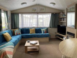 a living room with a blue couch and a table at 23 The Lawns Pevensey Bay Holiday Park in Pevensey