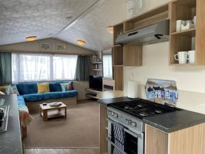 a kitchen and living room with a stove and a couch at 23 The Lawns Pevensey Bay Holiday Park in Pevensey