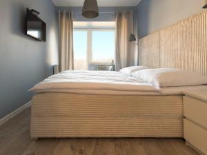 a large bed in a bedroom with a window at VacationClub - Leśna 12A Apartament 25 in Pobierowo