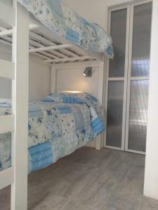 Un dormitorio con una litera con sábanas azules y blancas en Hostería Robert en Villa Gesell