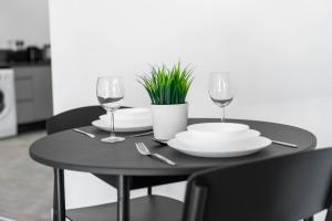 une table noire avec des assiettes et des verres et une plante dans l'établissement Stylish Apartment with Free Wifi & Netflix 49aG, à Rowley Regis