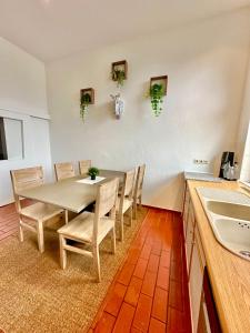 a dining room with a table and chairs and a kitchen at Ferienhaus Weserblick am Sandstrand mit Dart, Billard und Tischkicker in Berne