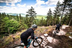 two people riding bikes on a trail in the woods at Mont-Blanc Ski In Ski Out and Beach in Saint-Faustin