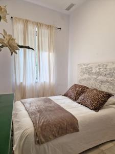 Dormitorio blanco con cama y ventana en Calzada 10, en Sevilla