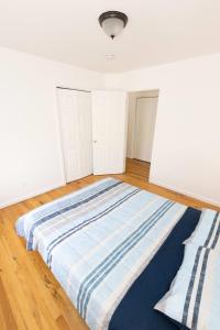 duże łóżko w pokoju z białymi ścianami i drewnianą podłogą w obiekcie Stylish & Spacious 3-bed Apt mins to NYC w mieście Jersey City