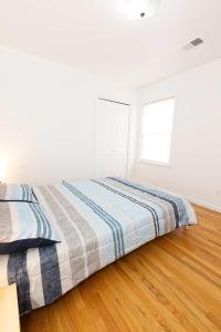 biała sypialnia z 2 łóżkami i drewnianą podłogą w obiekcie Stylish & Spacious 3-bed Apt mins to NYC w mieście Jersey City