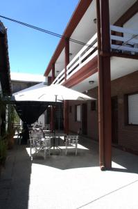 a patio with a table and chairs under an umbrella at Hostería Robert in Villa Gesell