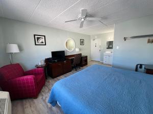 Sand Pebble Motor Lodge في بوينت بليزانت بيتش: غرفة نوم بسرير ازرق وكرسي احمر