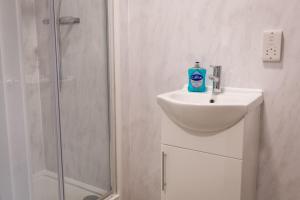 biała łazienka z umywalką i prysznicem w obiekcie Old Trafford : Stunning Studio w Manchesterze